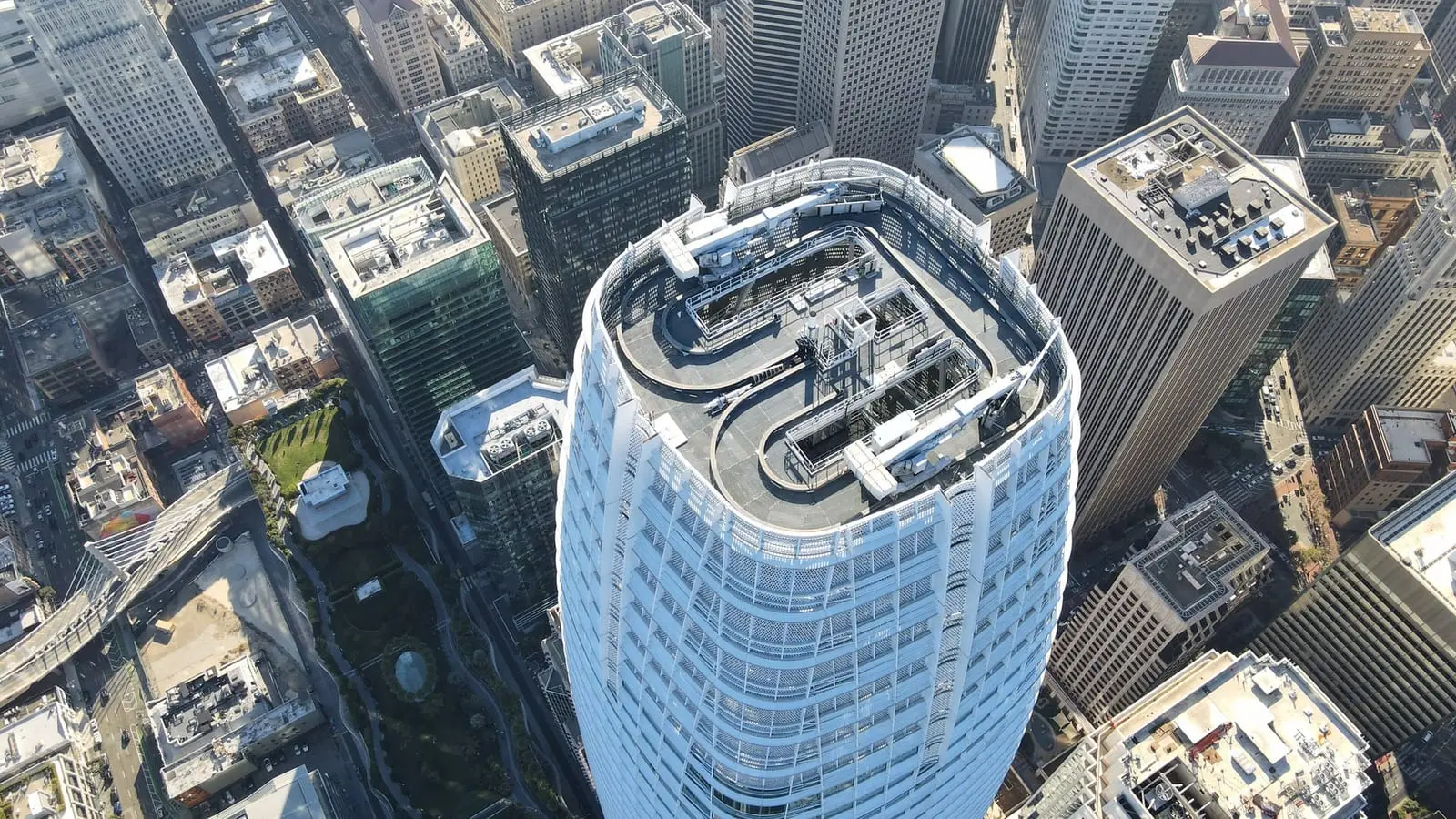 Aerial view of the rounded roof of Salesforce Tower in San Francisco with the surrounding downtown blocks below.